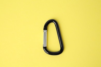 Photo of One black carabiner on yellow background, top view