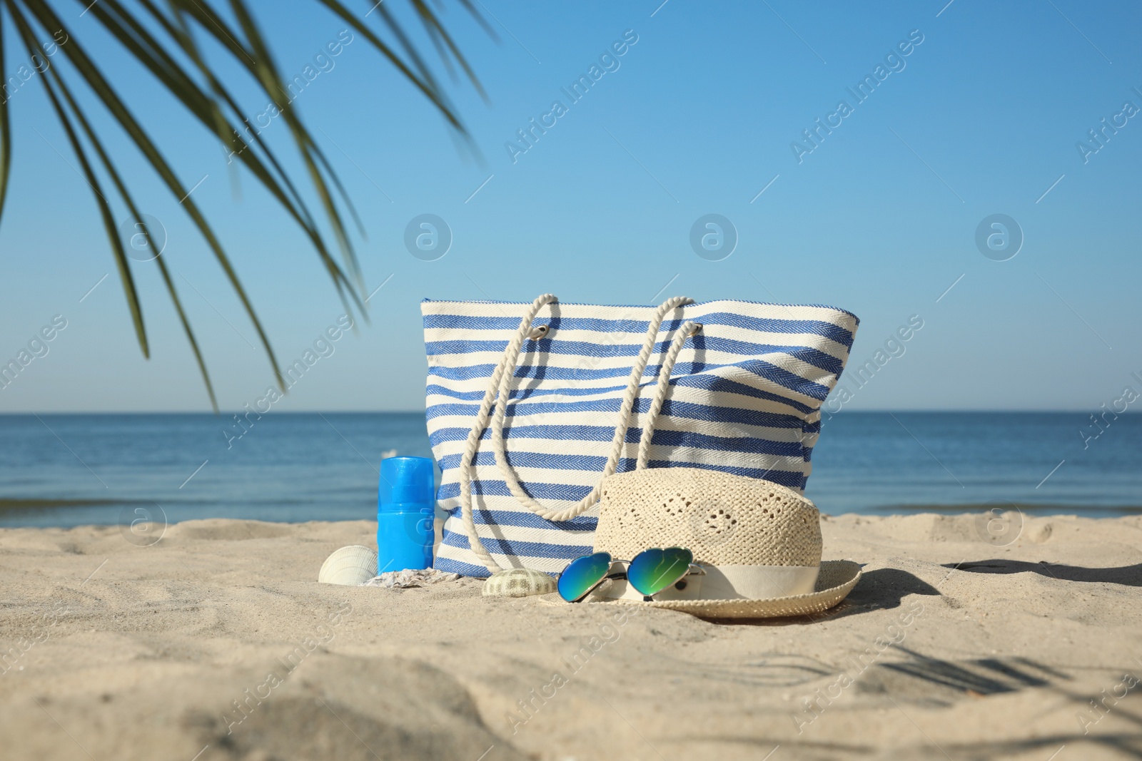 Photo of Stylish beach accessories on sandy sea shore