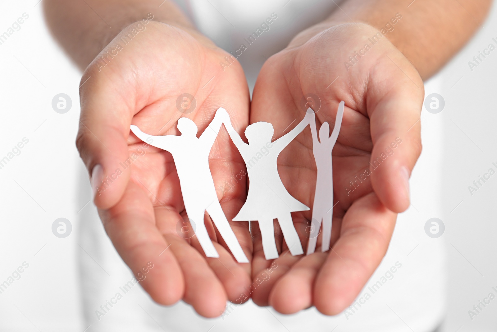 Photo of Young man holding paper family figure, closeup of hands