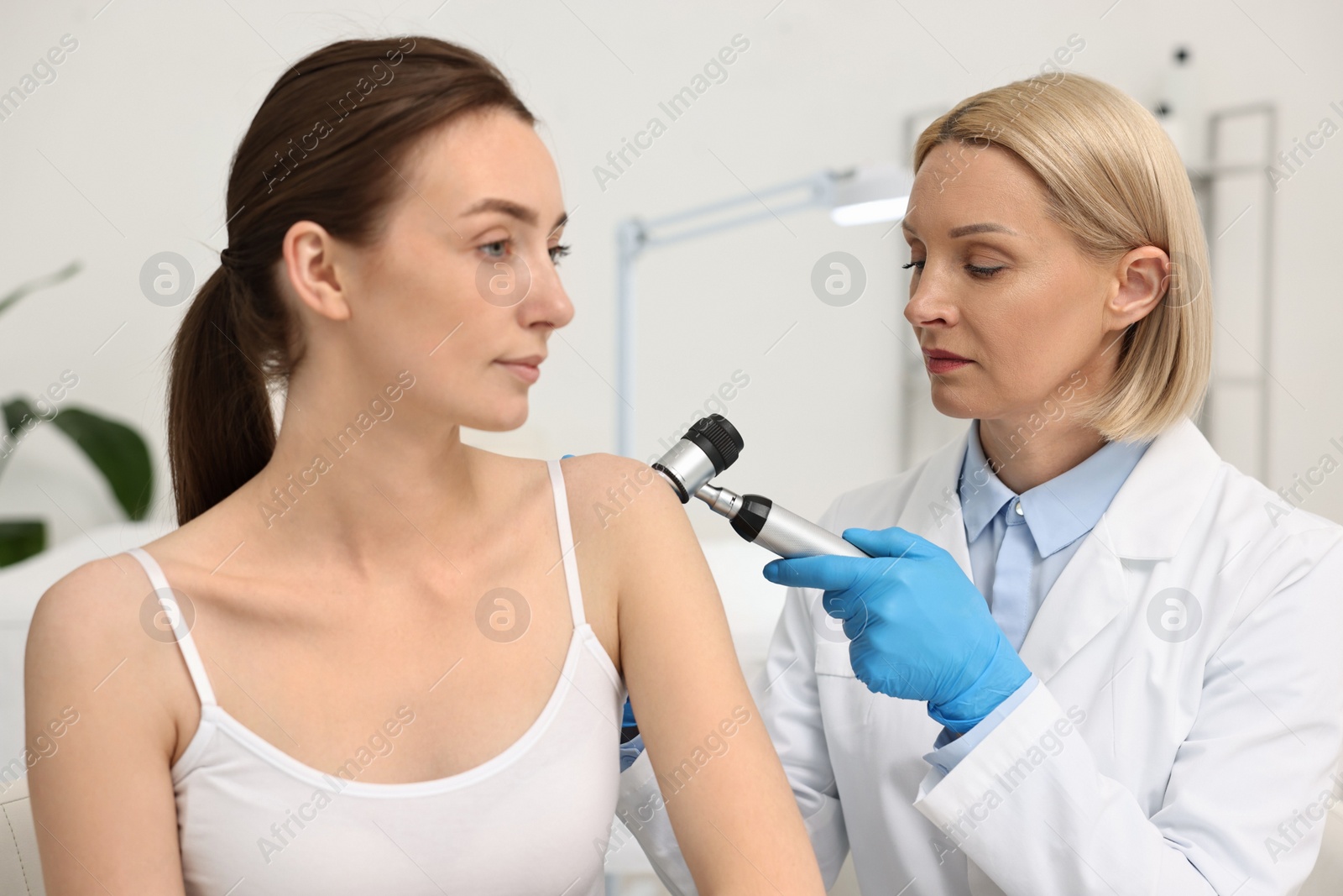 Photo of Dermatologist with dermatoscope examining patient in clinic