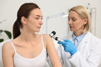 Photo of Dermatologist with dermatoscope examining patient in clinic