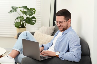 Photo of Man using laptop on couch at home