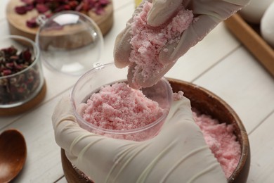 Photo of Woman in gloves making bath bomb at white table, closeup
