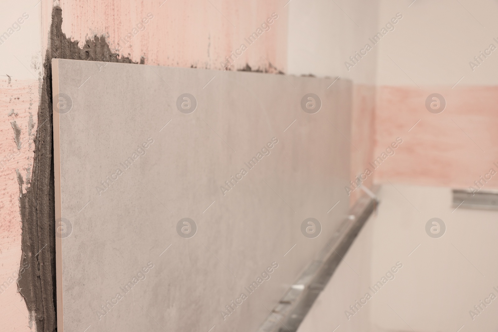 Photo of Adhesive mix and tiles on wall indoors
