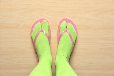 Woman wearing bright socks with flip-flops standing on floor, top view