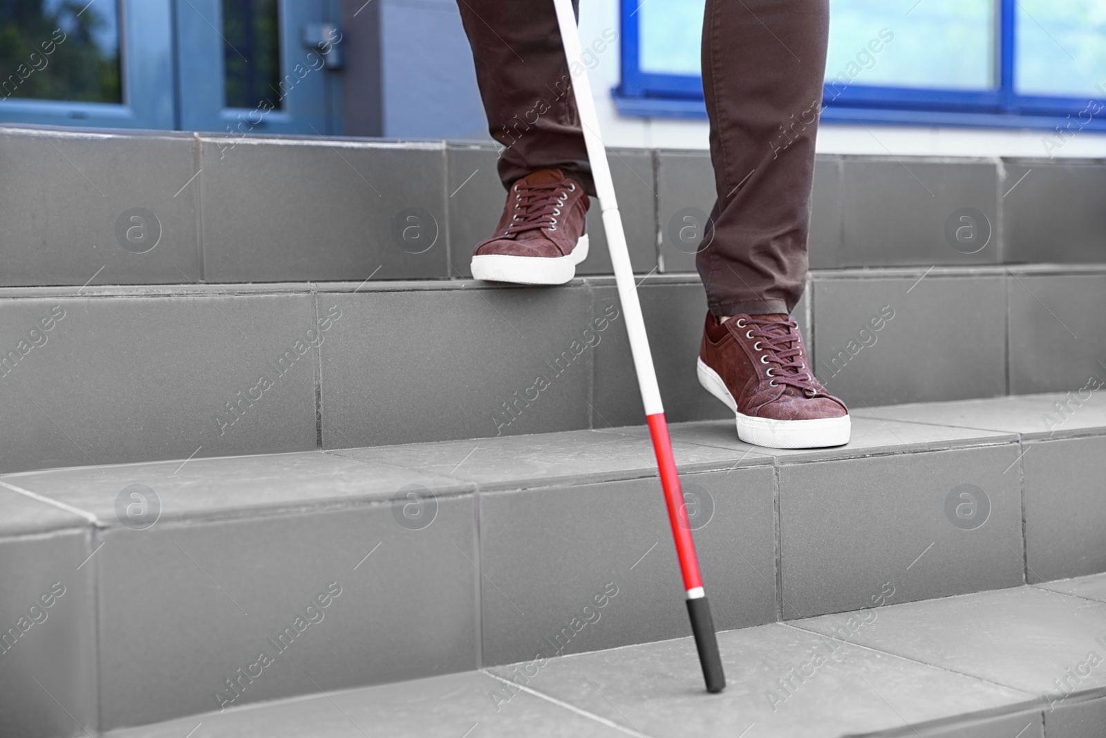 Photo of Blind person with cane going down stairs outdoors, closeup