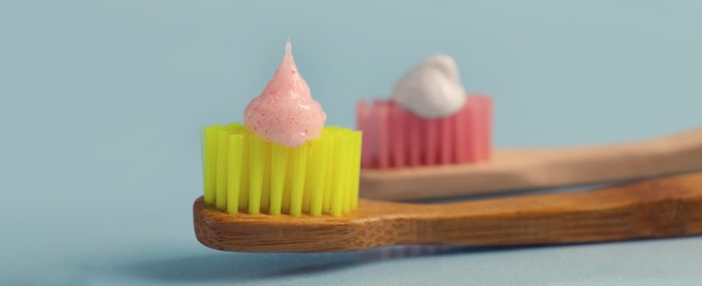 Image of Brushes with toothpastes on light blue background, banner design