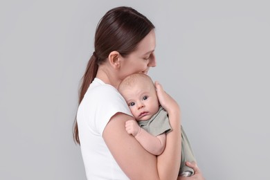 Photo of Mother with her cute baby on grey background