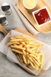 Delicious french fries served with sauces on light grey table, flat lay