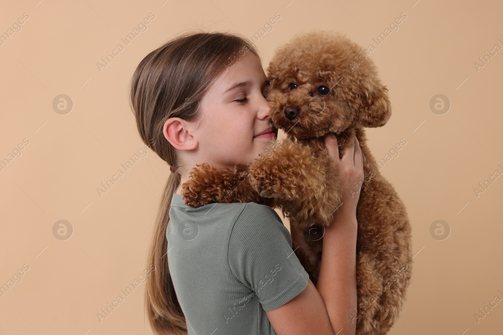 Photo of Little child with cute puppy on beige background. Lovely pet