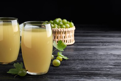 Tasty gooseberry juice on black wooden table. Space for text