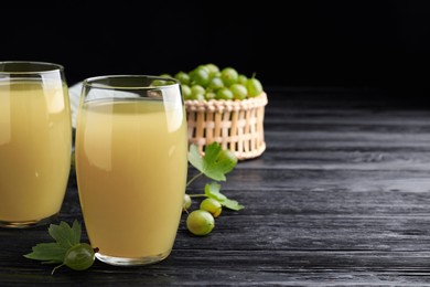 Photo of Tasty gooseberry juice on black wooden table. Space for text