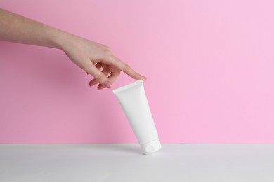 Photo of Woman with tube of cream on color background, closeup