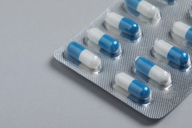 Photo of Pills in blisters on grey background, closeup. Space for text