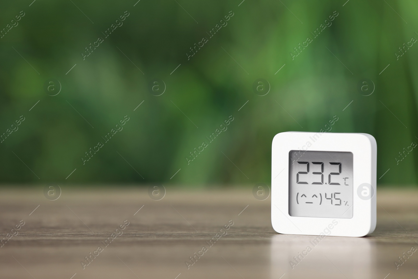 Photo of Digital hygrometer with thermometer on table against blurred background. Space for text