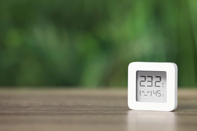 Photo of Digital hygrometer with thermometer on table against blurred background. Space for text