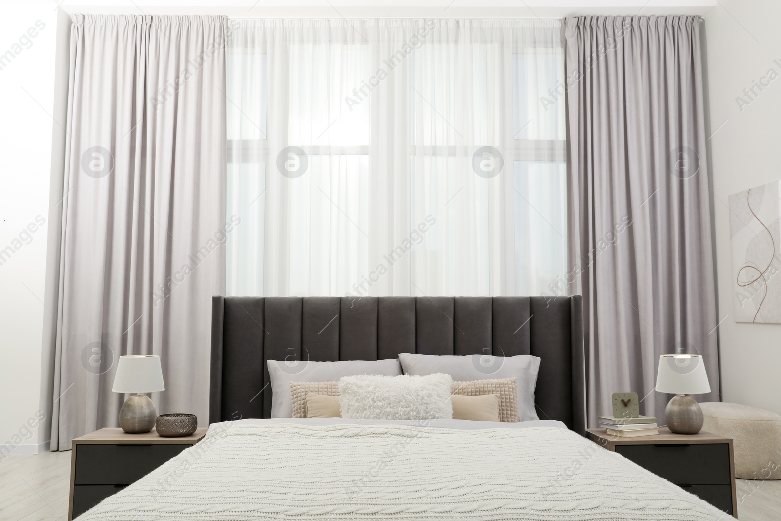 Photo of Stylish bedroom in soft light colors with comfortable bed and bedside tables. Interior design