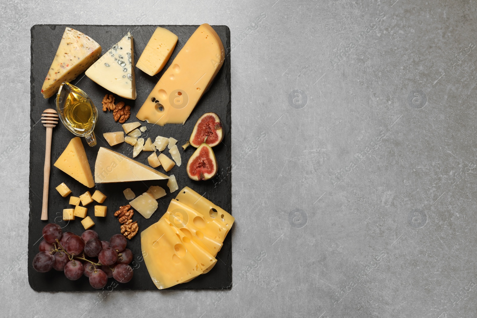 Photo of Different delicious cheeses served on grey table, top view. Space for text