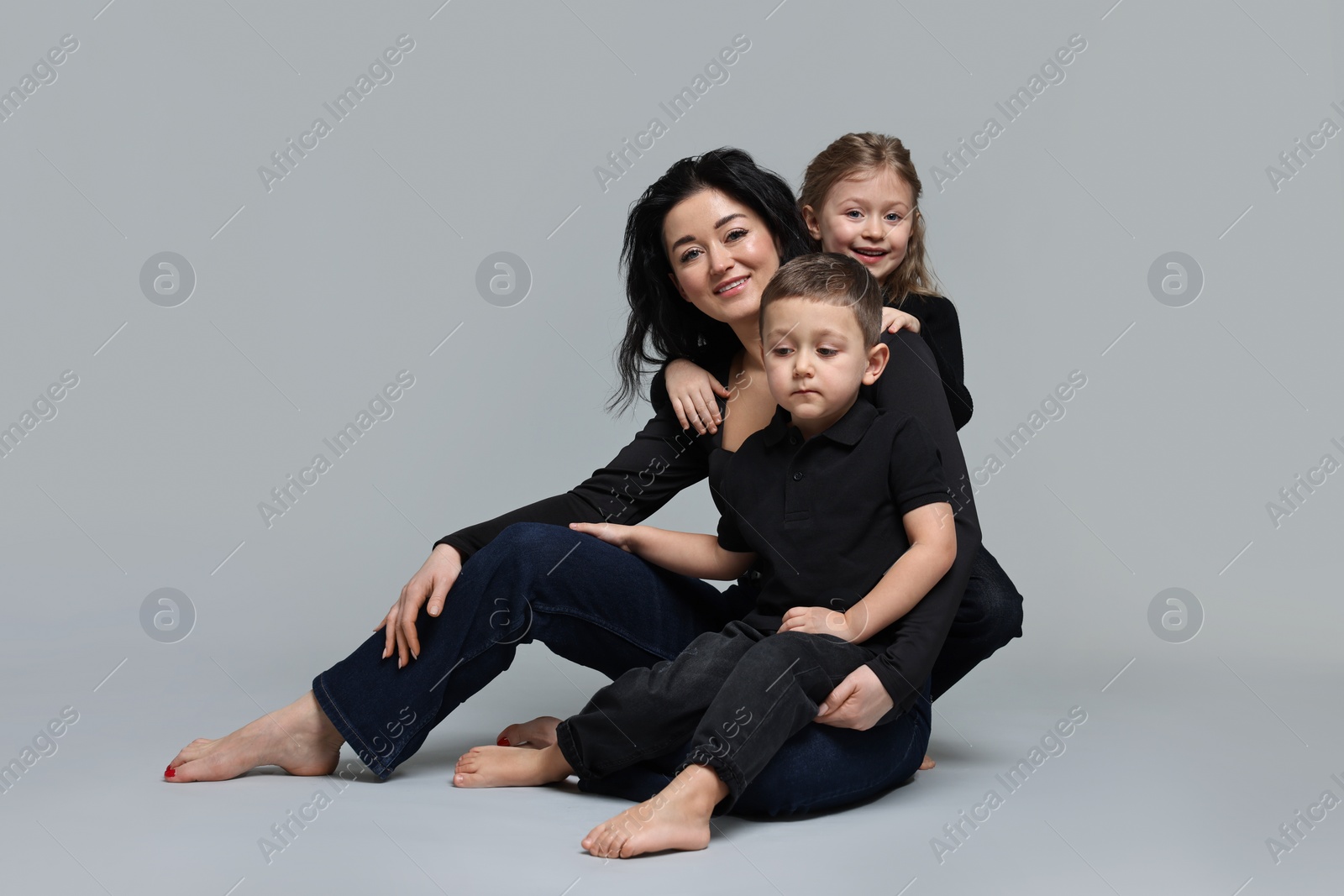 Photo of Little children with their mother on grey background