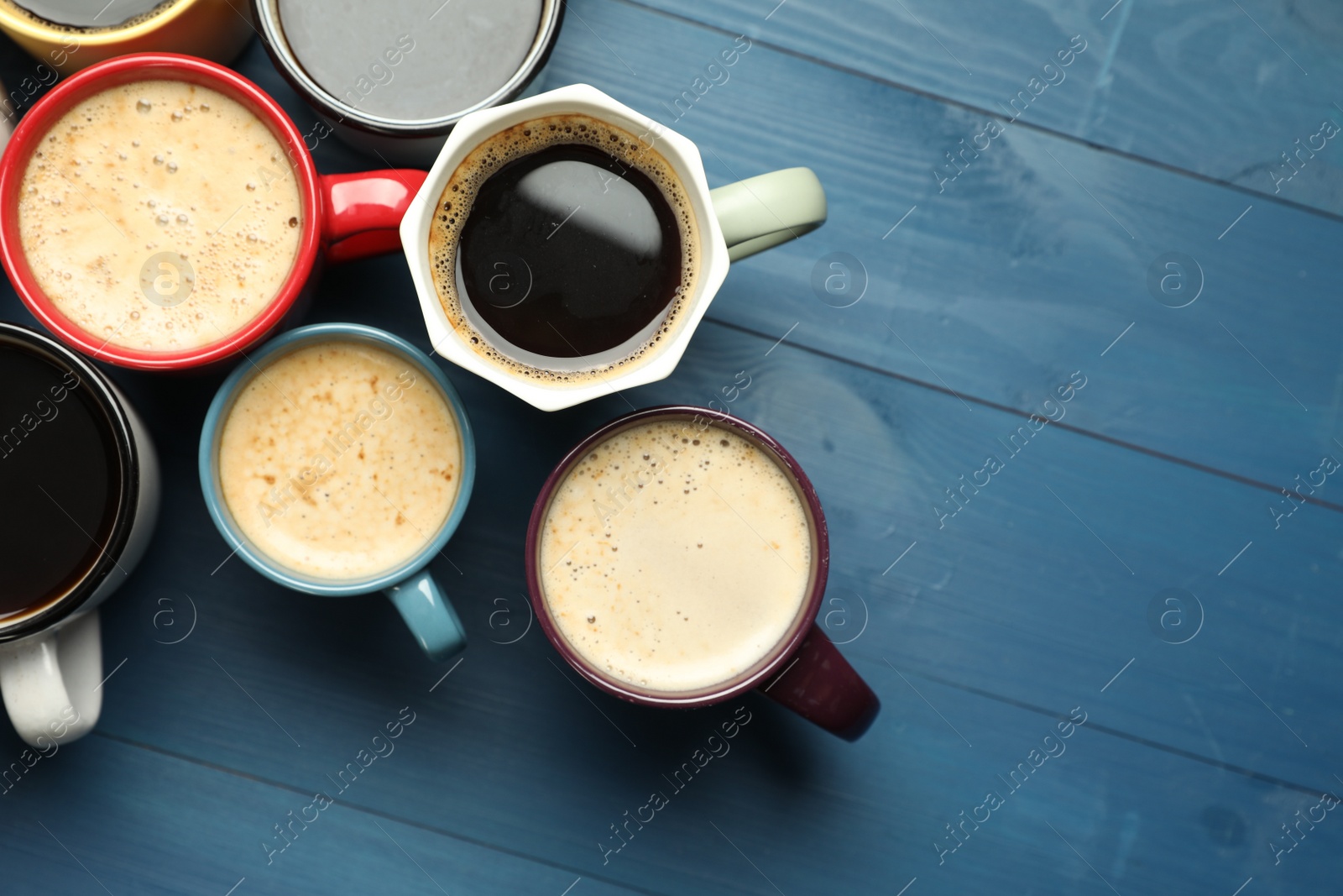 Photo of Many cups of different coffee drinks on blue wooden table, flat lay. Space for text