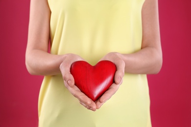 Photo of Woman holding decorative heart on color background, closeup