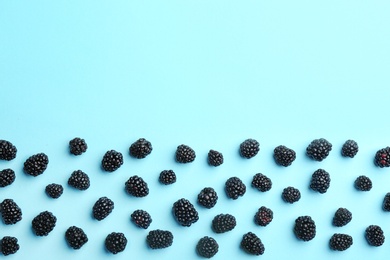 Fresh ripe blackberries on blue background, flat lay. Space for text