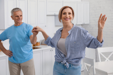 Photo of Happy senior couple dancing together in kitchen