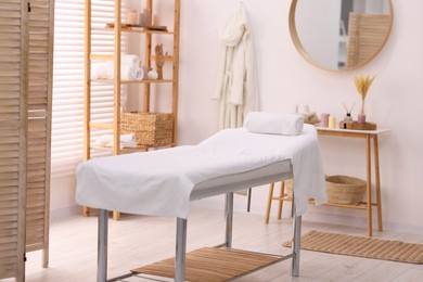 Photo of Comfortable massage table with clean towels in spa center