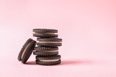 Photo of Tasty chocolate cookies with cream on color background. Space for text