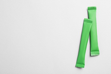 Green sticks of sugar on light grey background, flat lay. Space for text