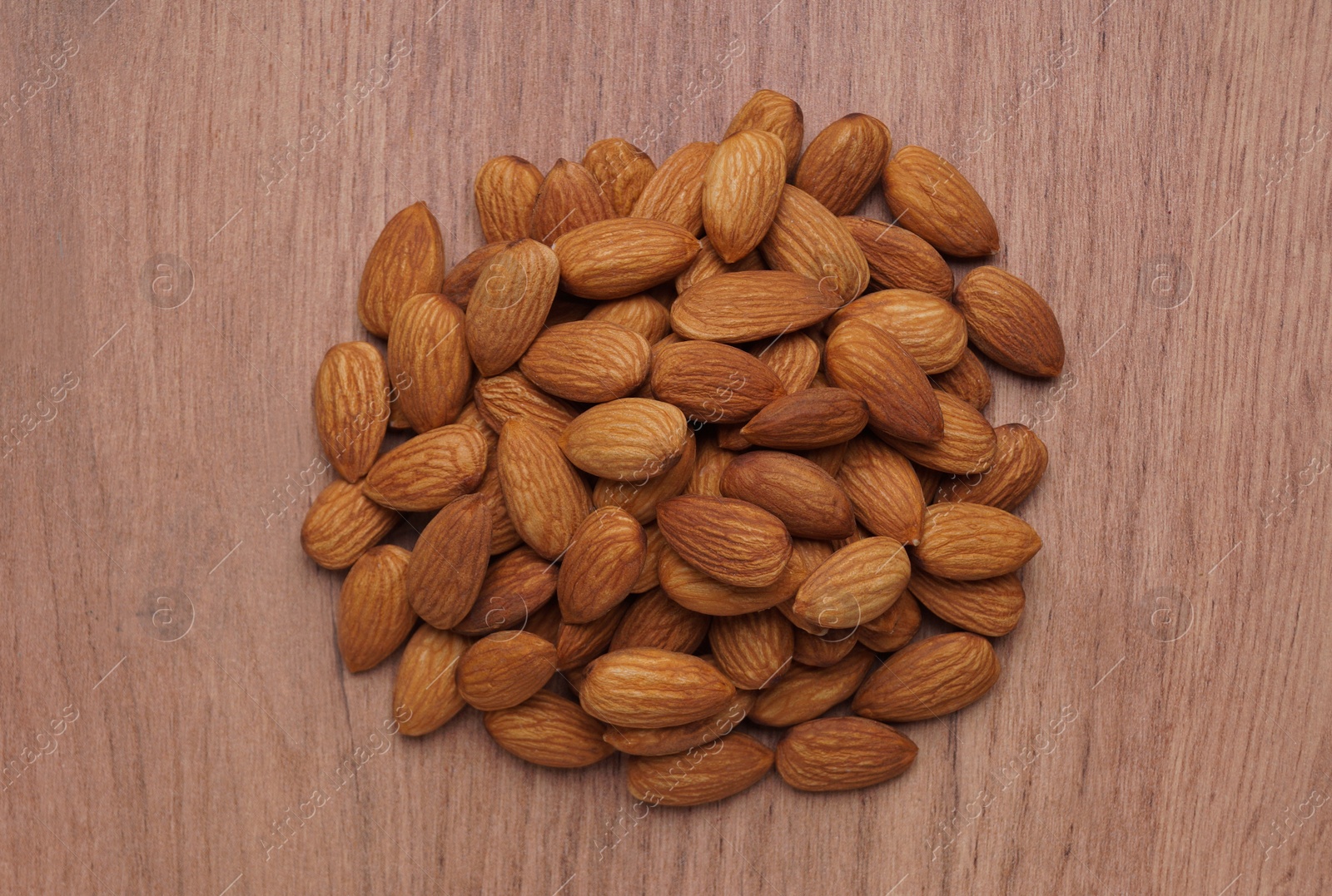 Photo of Pile of delicious almonds on wooden table, top view
