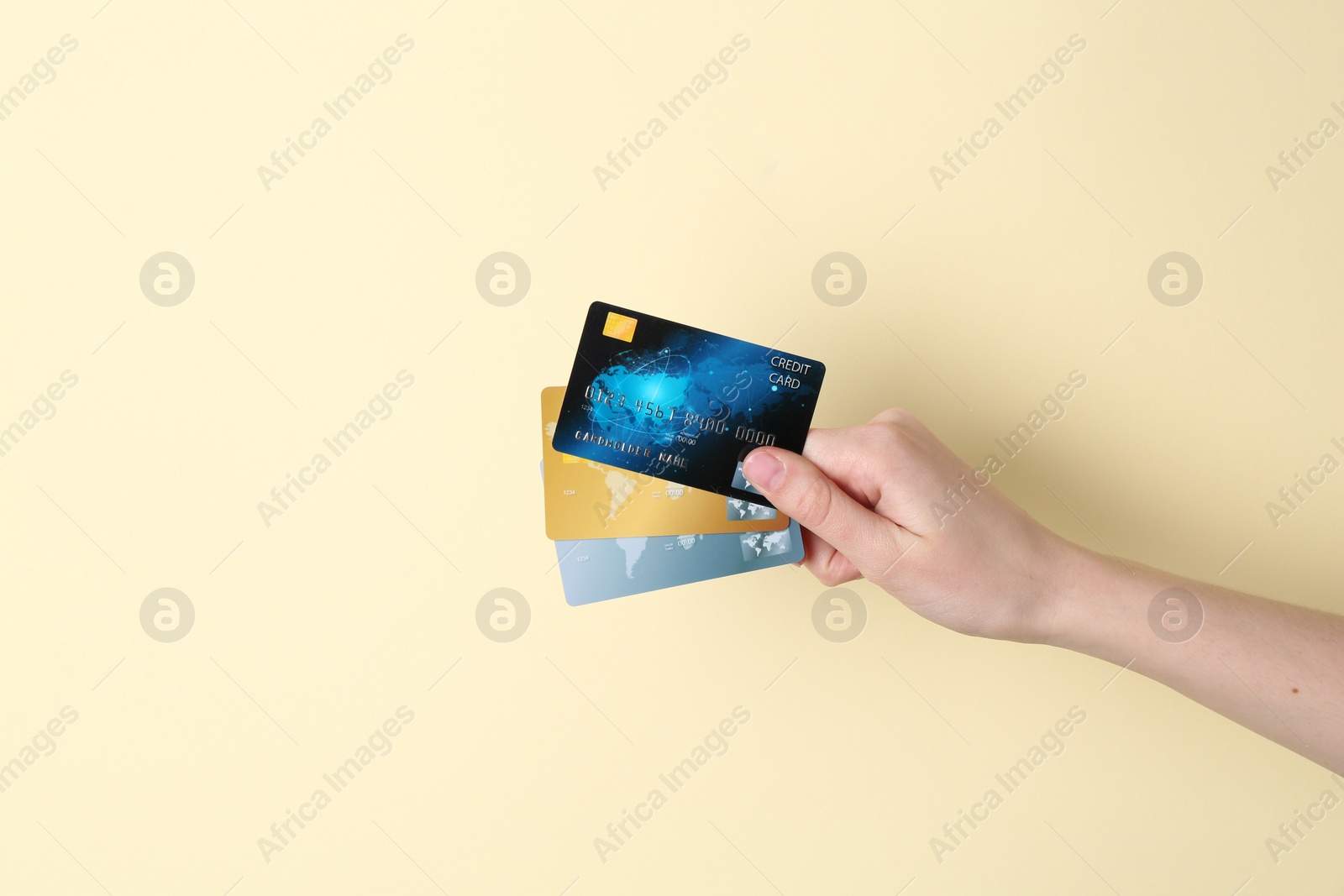 Photo of Woman holding credit cards on pale yellow background, closeup