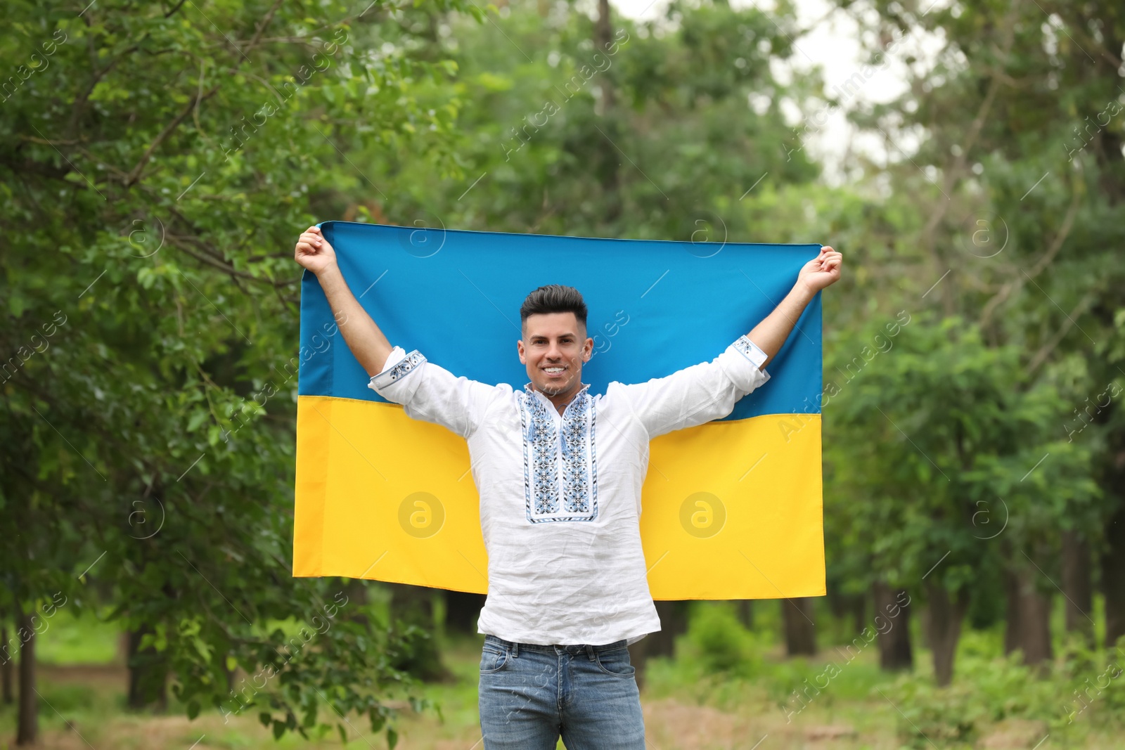 Photo of Man in vyshyvanka with flag of Ukraine outdoors