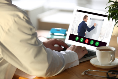 Doctor having online video consultation with business trainer at table, closeup