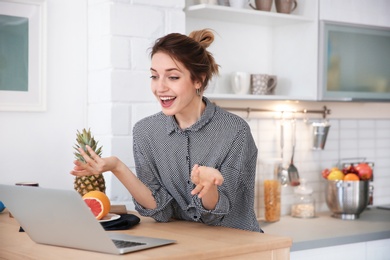Photo of Young blogger with fruits and laptop on kitchen
