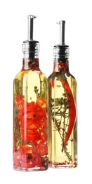 Glass bottles of cooking oil with spices and herbs on white background