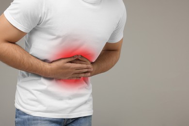 Image of Man suffering from stomach pain on grey background, closeup. Space for text