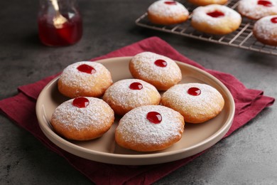 Photo of Hanukkah donuts with jelly and powdered sugar on grey table