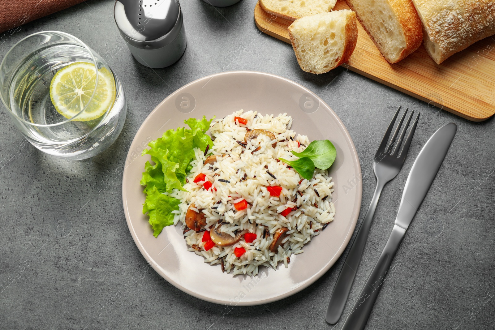 Photo of Delicious rice pilaf with mushrooms served on grey table, flat lay