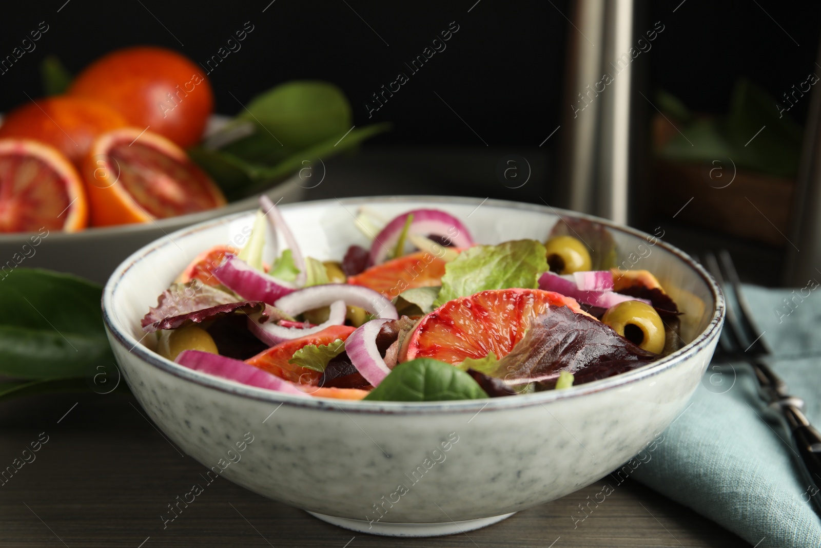 Photo of Bowl of delicious sicilian orange salad on wooden table, closeup