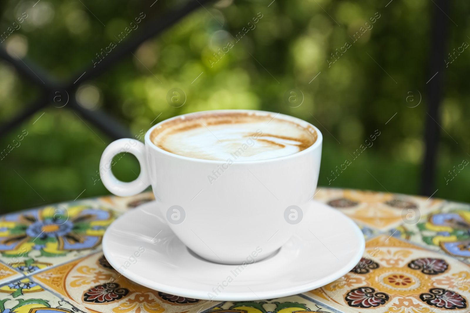 Photo of Cup of aromatic coffee on beautiful table in cafe outdoors