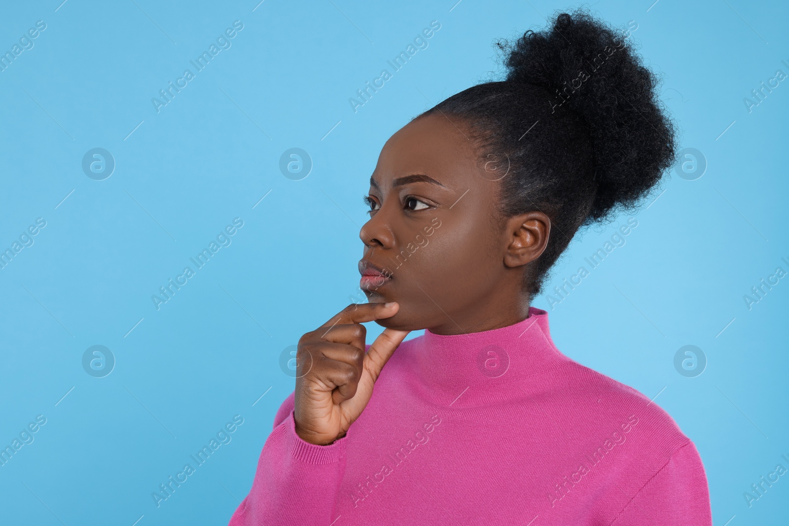 Photo of Portrait of concentrated young woman on light blue background. Space for text