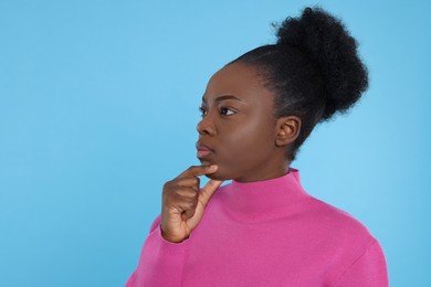 Photo of Portrait of concentrated young woman on light blue background. Space for text