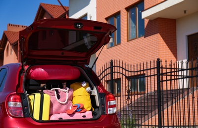 Photo of Family car with open trunk full of luggage in city. Space for text