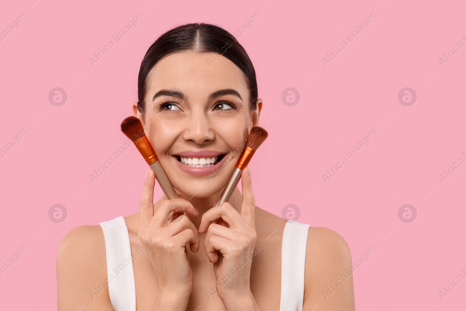 Photo of Happy woman with different makeup brushes on pink background. Space for text