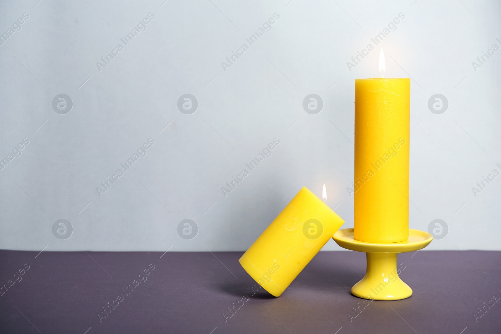 Photo of Decorative wax candles on table against light background