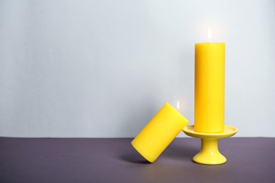 Photo of Decorative wax candles on table against light background