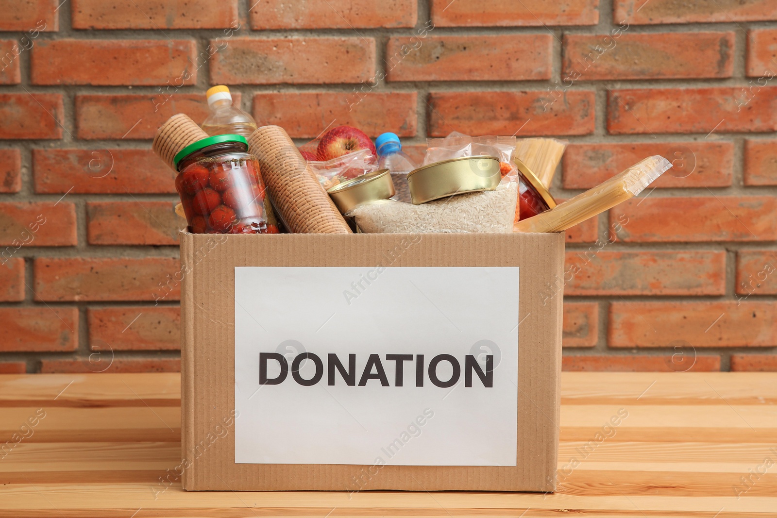 Photo of Donation box with food on table near brick wall