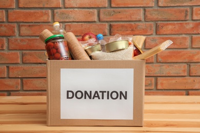 Photo of Donation box with food on table near brick wall