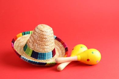 Mexican sombrero hat and maracas on red background